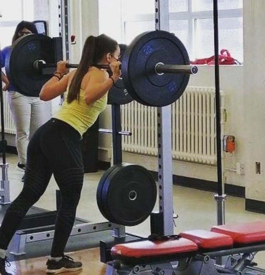 A Roudfit client performing a barbell back squat in the gym
